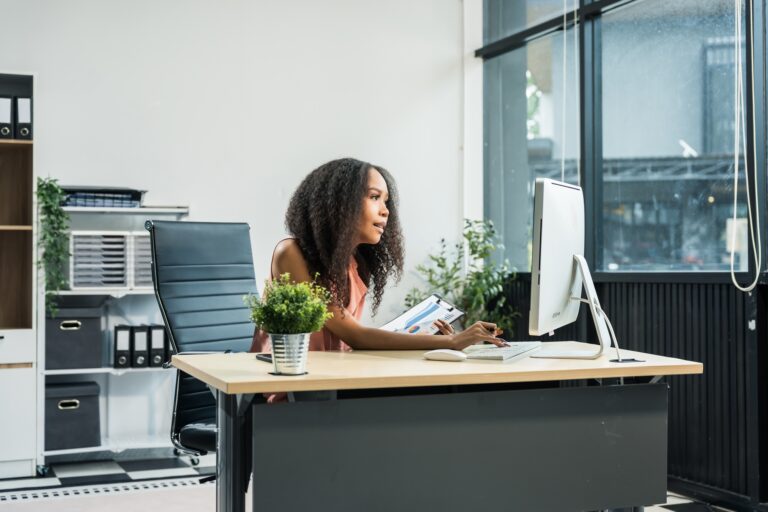 African American woman with afro at desk, managing finance, market research, investors for startup.