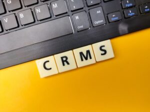 Black keyboard and toys word with the word CRMS on yellow background.