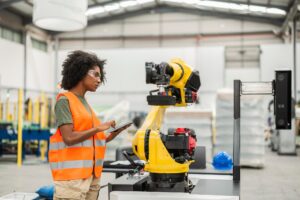 Female engineer programming robotic arm in factory