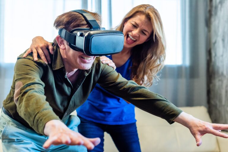 Mature married couple at home playing with virtual reality glasses.