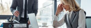Panoramic shot of businesswoman looking at laptop near folder with crisis management and businessman