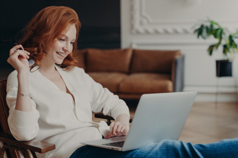 Skilled positive female student creats article for homework, sits in coworking space