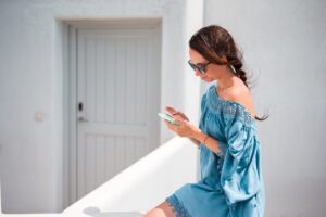 Woman with cellphone outdoors on the street. Tourist using mobile smartphone